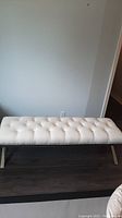 Front view of white fabric tufted bench showing overall design and cushion.
