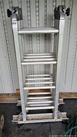 Full front view of the folded 16 ft Featherlite convertible ladder showing rungs and locking knobs.