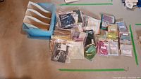 Overview of 41 assorted cross stitch fabric pieces in individual resealable bags with turquoise plastic organizer