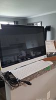 Dell all-in-one desktop computer on counter with white keyboard and power cable coiled