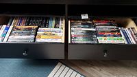 Two open drawers filled with a variety of DVD cases showing spines with visible titles for easy readability.