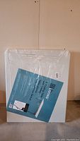 Photo of the folded table in plastic packaging, showing the front face with label.