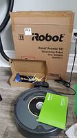 Front view of Roomba 652 unit, original box and spare brush accessories in cardboard tray