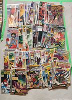 Display of assorted Spider-Man comics including The Amazing Spider-Man and The Spectacular Spider-Man in protective plastic sleeves laid out on a surface.