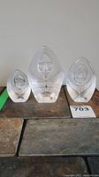 Three Mats Jonasson lead crystal Inuit carvings arranged on a surface, showing front faces and part of their etched detail patterns.