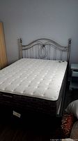 Full view of queen bed with mattress, box spring, metal headboard and frame