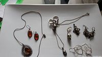 Top view of sterling silver jewelry pieces including earrings, necklaces and rings laid out on tray.