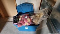 Blue plastic bin filled with yarn skeins and other crafting supplies