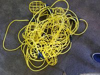 Coiled yellow string work light with 10 bulb protective cages visible, showing overall condition and length.