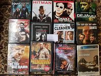 First photo showing 11 DVDs laid out in three rows on a carpet including Hancock, Hitman, Cradle to the Grave, Deja Vu, 300, American Gangster, The Cleaner, Boondock Saints, Live Free or Die Hard, The Rundown, 2 Fast 2 Furious.