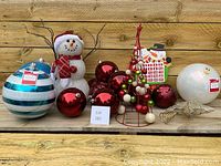 Full lot photo showing all items together including snowman, blue and white balls, red balls, metal tree, wooden advent calendar and tree topper