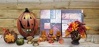 Wide view of the full fall decor collection including the metal jack o lantern, canvas panels, candle holders, pine cone arrangement, and decorative pumpkins.