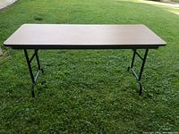 Top view of the rectangular folding table with wood-look laminate surface on green grass.