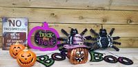 Assorted Halloween themed decor including jack o lantern figurines, signs, spider decoration, and cushioned mat.