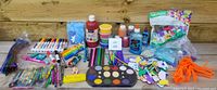 Wide view showing all arts and crafts supplies including markers, crayons, colored pencils, paints, paint brushes, chenille stems, foam letters and numbers, wooden letters and numbers, glitter glue, and other craft materials spread out on a wooden surface.