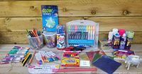Full lot overview showing multiple colorful pens, pencils, markers, paints, prismatic papers, glow stars, beads, and unicorn figure