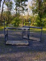 Full view of two blue metal shelf units outside on gravel with trees in background