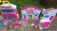 Photo showing three colorful Shopkins mall buildings and various small furniture pieces placed on the ground.