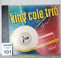 Front view of King Cole Trio Vol. 2 album cover with vintage graphic art including a violin, piano, and trumpet