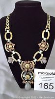 Full view of the Alexandra statement necklace on black display bust showing brass chain link and stone clusters.