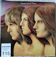 Front cover of Emerson Lake & Palmer Trilogy double LP album with illustrated profiles of three band members.
