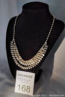 Full view of the three-strand gold-colored necklace displayed on a black mannequin bust.