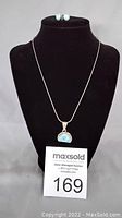 Full view of pendant necklace and stud earrings on black display bust