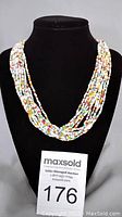 Full front view of the 11-strand multicoloured glass beads necklace on black display bust showing bead colours and strand arrangement.