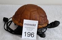 Front right angled view of the turtle lamp showing cast iron base and tortoise shell patterned glass shade, with auction tag.