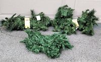 Three bundles of new pine garlands laid out on the ground showing length and fullness.