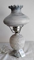 Full view of the ceramic light blue table lamp showing the overall shape, ruffled shade edge, and marbled finish.