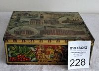 Top and side view showing ornate illustrations of historic buildings and decorative borders on gold-tone biscuit tin.