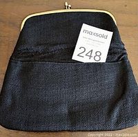 Front view of the black tweed evening bag with visible front pocket and gold frame clasp.