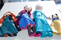 Four Disney princess plush dolls laid on table: Anna, Elsa, Merida, Snow White