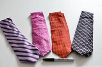 Four men's neckties arranged flat beside a marker, showing colors and patterns: purple striped, pink patterned, orange textured, black geometric.