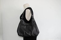 Side profile of black leather purse on mannequin showing shape and strap length.