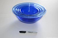 Photo of all four blue Pyrex bowls nested inside each other with a black marker for size reference