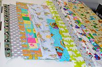 Multiple pieces of colorful cotton quilting fabric with various kids-themed patterns such as dogs, birds, and blocks, laid out to show variety and condition.