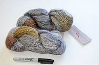 Two skeins of maiden hair yarn showing variegated colors and texture alongside a Sharpie marker for scale.