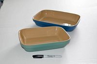 Two rectangular ceramic baking dishes with a Sharpie for size reference; one smaller green, one larger blue, both with beige interiors.