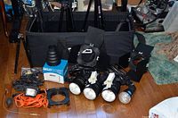 Overview of studio lighting kit laid out on floor showing four monolights, two stands, barn doors, cables and carrying case
