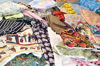 Multiple quilting fabric pieces spread out showing various patterns and colors including florals, stripes, paisley, and holiday prints.