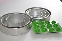 Four round aluminum cake pans nested together, showing size differences.