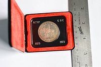 Front side of the 100th anniversary RCMP silver dollar coin, showing mounted officer and dates 1873-1973 with ruler for scale.