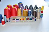 All thread cones and spools arranged on a flat surface with plastic storage case visible