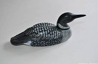 Full side view of painted wooden loon figurine showing detailed feather paintwork and form resembling a loon bird.