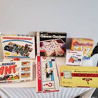 Photo of seven vintage board games and electronic snap kits including Monopoly, Chinese Checkers, Fantastic Gymnastics, Hungry Ant, and building kits.