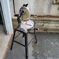 Front side view of Craftsman chop saw on black metal stand outdoors.