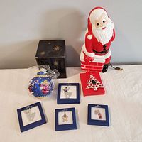 Lot with vintage blow mold Santa on chimney, Swarovski boxed crystal ornaments, Lenox ceramic tree ornament, and large blue glass Santa ornament wrapped in plastic