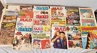 Photo shows assortment of comic books and magazines from 1980s including Mad, Star Trek, Cracked, Thriller, Whiz Kids, Cartoons, Warlord, Spider, and Whizzer and Chips with colorful illustrated covers.